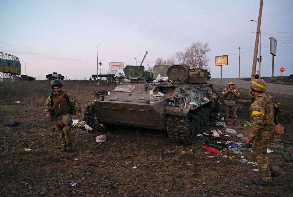 Ukrainian soldiers next to a destroyed armoured vehicle, which they said belongs to the Russian army, outside Kharkiv. 