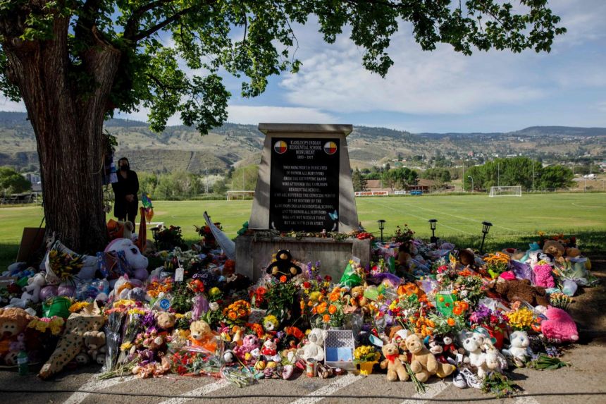 A makeshift memorial honouring the 215 children surrounds a monument outside the former Kamloops Indian Residential School on June 2, 2021.
