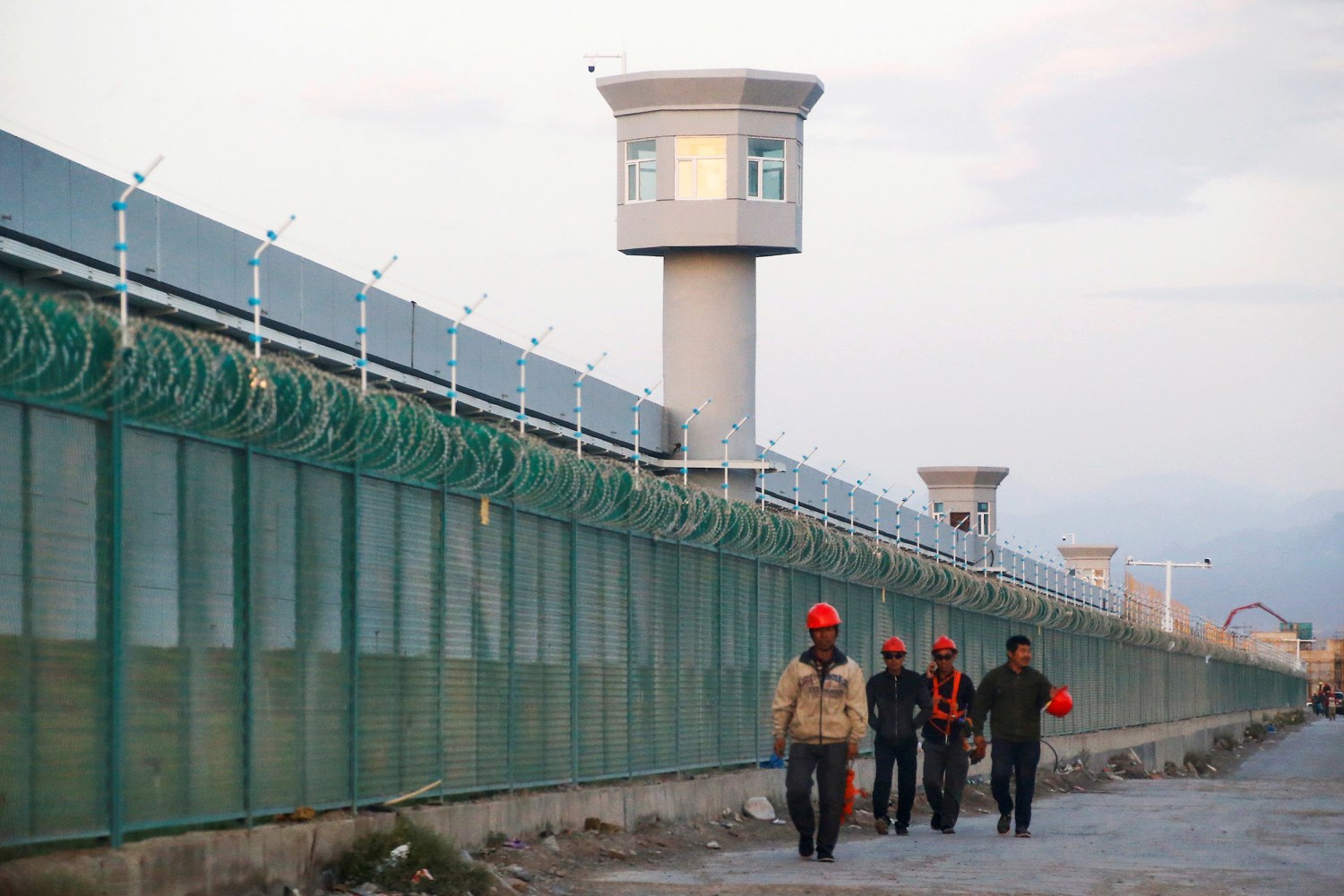 Workers walk by the perimeter fence of what is officially known as a vocational skills education centre in Dabancheng in Xinjiang Uyghur Autonomous Region, China.